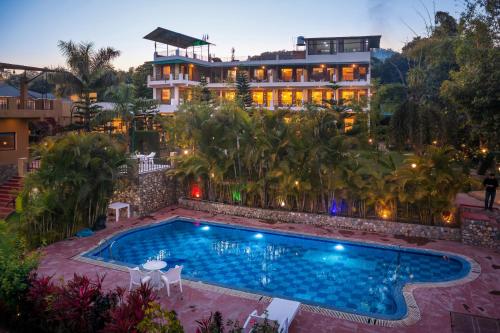 a hotel with a swimming pool in front of a building at Dee Fellows Riverside Resort in Garjia