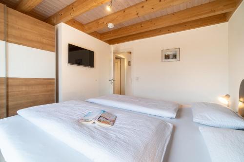 a bedroom with two beds and a tv on the wall at Kapitänskoje in Greetsiel