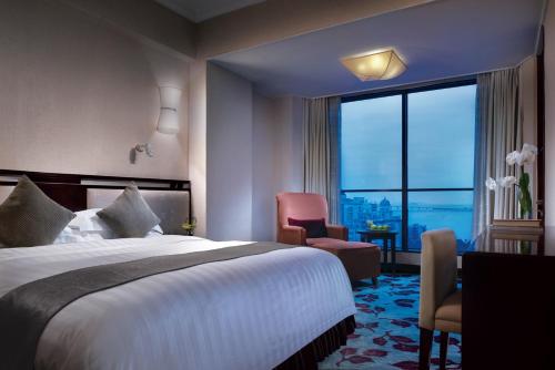 a hotel room with a bed and a large window at Guangdong Hotel (Zhuhai) in Zhuhai