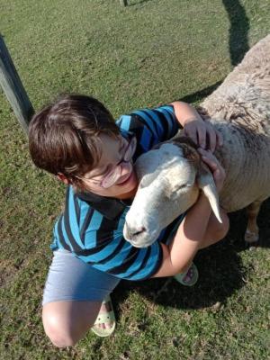 a young boy is hugging a sheep at Trees&Seas - Glamping with farm animals in Wilderness