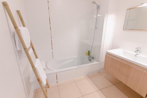 a bathroom with a shower and a tub and a sink at Cozy Nest By the Zoo in Mulhouse
