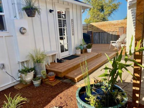 a porch with potted plants and a wooden deck at Charming Cuvée Cottage, 2 blocks to downtown! in Carlton