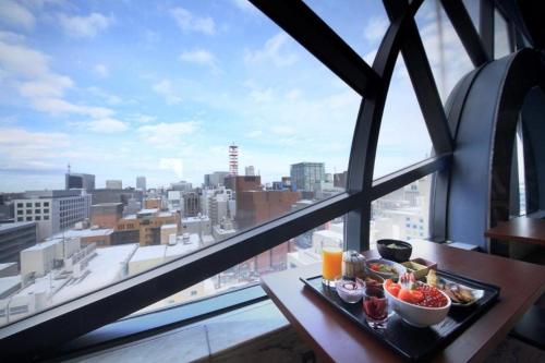 una bandeja de comida en una mesa frente a una ventana en Nest Hotel Sapporo Odori, en Sapporo