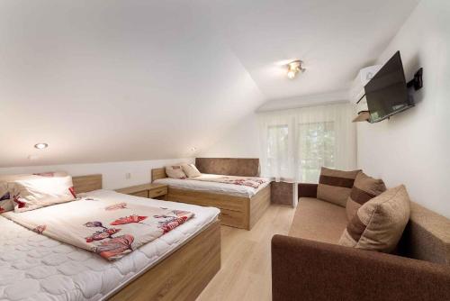 a room with two beds and a couch and a tv at Holiday home in Balatonmariafürdo 40847 in Balatonmáriafürdő