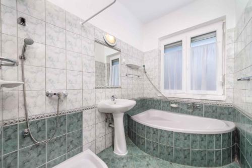 a bathroom with a bath tub and a sink at Holiday home in Balatonmariafürdo 40848 in Balatonmáriafürdő