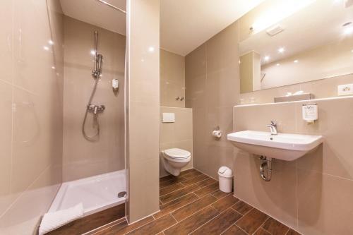 a bathroom with a sink and a shower and a toilet at Hotel Excelsior Dortmund Hauptbahnhof in Dortmund