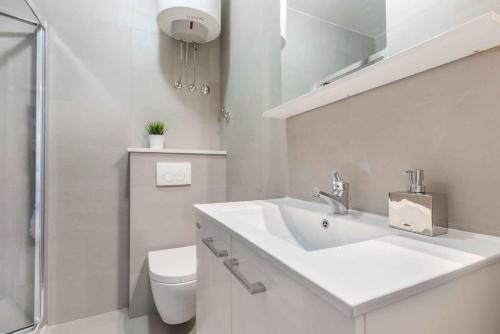 a white bathroom with a sink and a toilet at Apartment in Rabac 43550 in Rabac