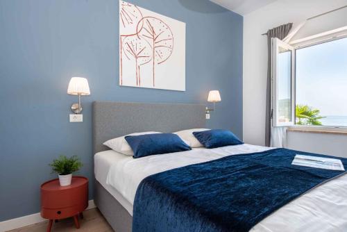 a bedroom with a bed with blue walls and a window at Apartment in Rabac 43550 in Rabac