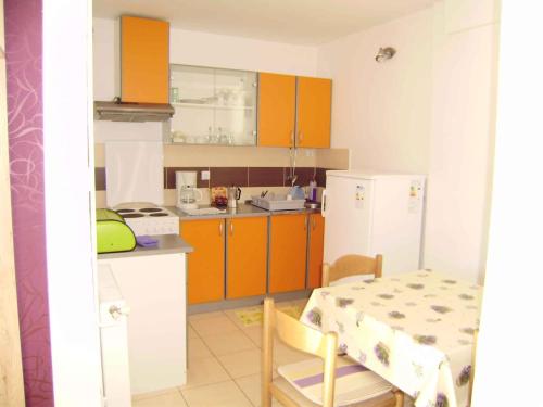 una cucina con armadi arancioni, tavolo, tavolo e tavolo di Apartment in Cavle 38810 a Čavle