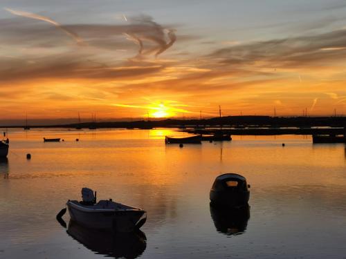 two boats sitting in the water at sunset at AnchorageWells Lodge, Seaview Apartment in Wells next the Sea