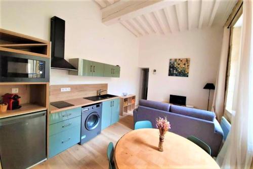 une cuisine et un salon avec une table et un canapé dans l'établissement Appartement à deux pas de la place du forum, à Arles
