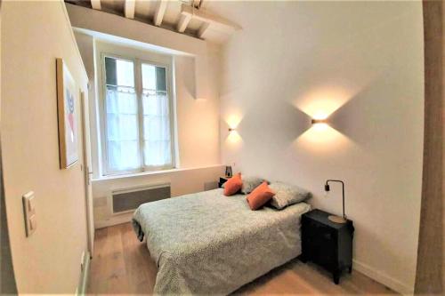 a bedroom with a bed with two pillows and a window at Appartement à deux pas de la place du forum in Arles