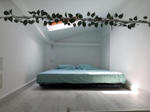 un lit dans une chambre avec une branche à feuilles dans l'établissement spacieux logement vieil antibes climatisé 5 minutes plages, à Antibes