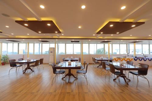 a dining room with tables and chairs and windows at VOVO HOTELS in Yelahanka