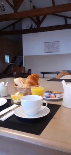 einen Tisch mit einer Tasse Kaffee, Brot und Orangensaft in der Unterkunft Domaine du chauvet in Sainte-Eulalie