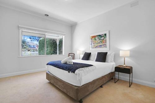 a white bedroom with a large bed and a window at Lovely 3BR House In Seaside Area in Williamstown