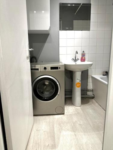 a small bathroom with a washing machine and a sink at Jolie appartement duplex 2 min gare-Disney et paris 15 min in Noisy-le-Grand