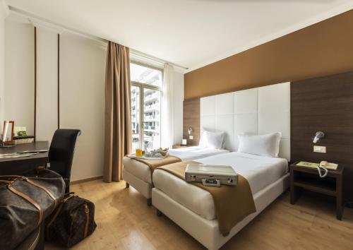 una camera d'albergo con un grande letto e una scrivania di Ambassador-Monaco a Monte Carlo