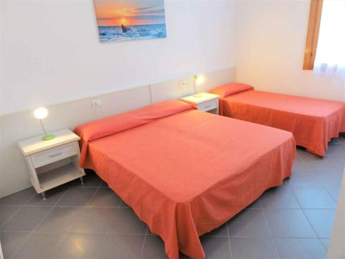 2 Betten in einem Zimmer mit orangefarbener Bettwäsche in der Unterkunft Holiday Homes in Bibione 36266 in Bibione