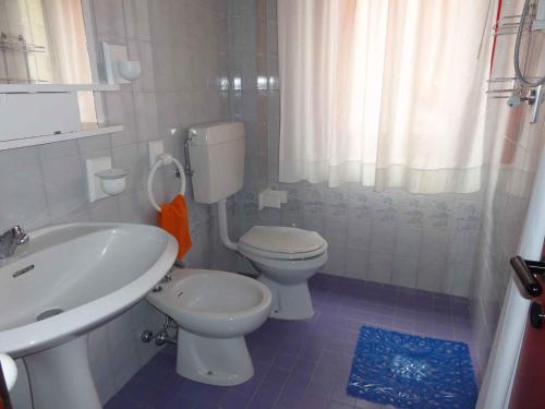 ein weißes Bad mit einem WC und einem Waschbecken in der Unterkunft Apartment in Bibione 38277 in Bibione