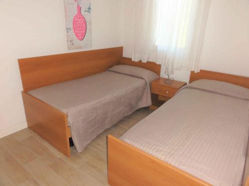 um pequeno quarto com 2 camas e uma mesa de cabeceira em Holiday home in Bibione 41088 em Bibione