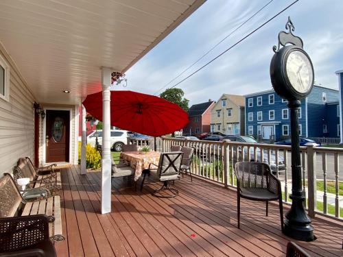 un porche con reloj, mesa y sillas en Inn on the Harbour en Charlottetown