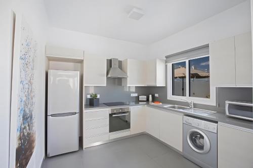 a white kitchen with a refrigerator and a dishwasher at Casa de Nicole in Protaras