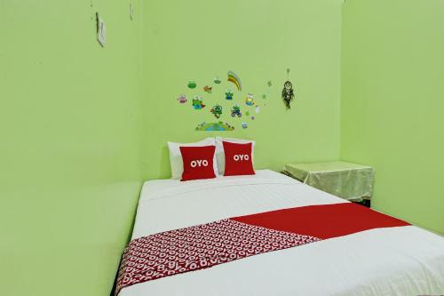 a bedroom with a bed with two red pillows at OYO 92467 Cahyo Kost 1 in Semarang