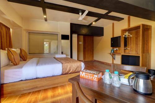 a bedroom with a bed and a wooden table with a desk at Platinum Hotel in Turambhe