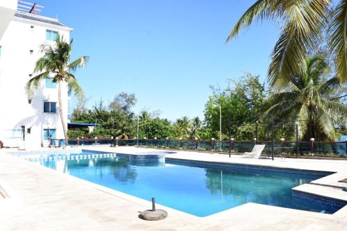 博卡奇卡的住宿－Dream Village Boca Chica frente a la playa，一座棕榈树游泳池和一座建筑