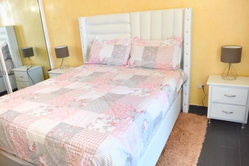 a bedroom with a bed with a pink and white comforter at Dream Village Boca Chica frente a la playa in Boca Chica