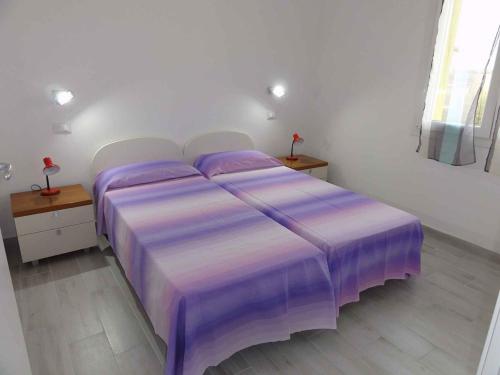 een paars bed in een witte kamer met 2 tafels bij Apartment in Bibione 38316 in Bibione