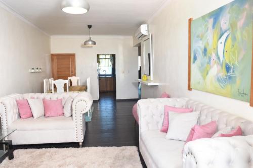 a living room with two white couches and pink pillows at Dream Village Boca Chica frente a la playa in Boca Chica