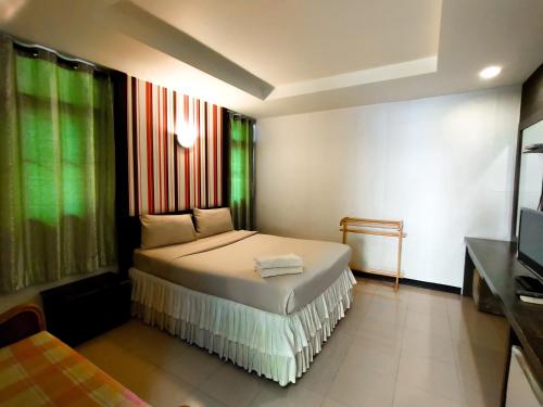 Dormitorio pequeño con cama y TV en Srisomthai Hotel en Ubon Ratchathani