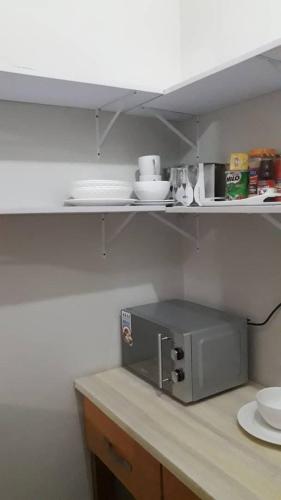 a kitchen counter with a microwave on a shelf at Spacious Holiday Let Wi-Fi & Private Amenities Oyibi in Oyibi