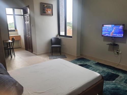 a bedroom with a bed and a flat screen tv at Spacious Holiday Let Wi-Fi & Private Amenities Oyibi in Oyibi