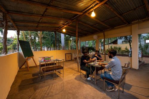 un groupe de personnes assises à des tables dans un patio dans l'établissement Avadale Tadoba - Stag Groups Not Allowed, à Mohurli