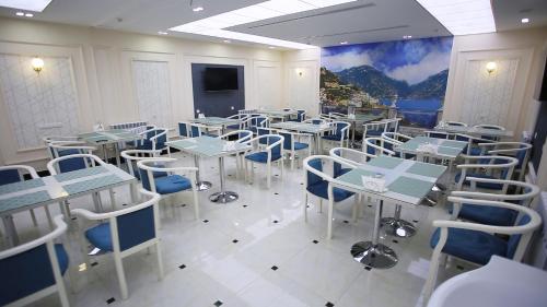een restaurant met witte tafels en blauwe stoelen en een muurschildering bij Muxlis Hotel in Tasjkent