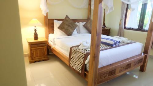 a bedroom with a bed and a table with a lamp at Buana Ubud Inn in Ubud