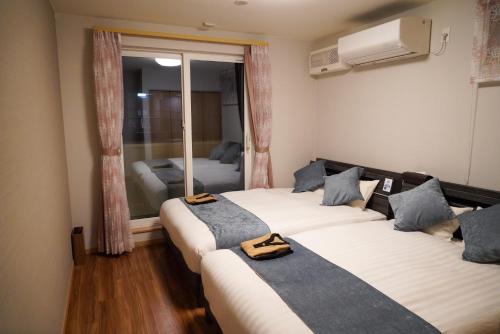 函館市にあるHakodate MOTOMACHI guesthouseのベッド2台と窓が備わる客室です。