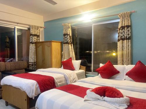 a hotel room with two beds and a window at Hotel Nightingale in Pokhara