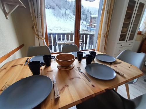 une table en bois avec des assiettes et des ustensiles dessus dans l'établissement Nice & cozy apartment facing the gondola - LA BOULE DE NEIGE 112, aux Contamines-Montjoie