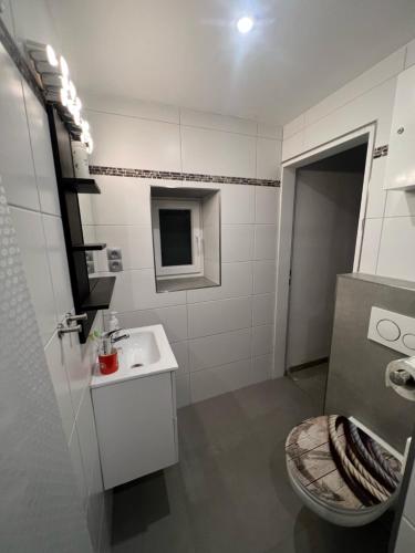 a white bathroom with a toilet and a sink at Ferienhaus Mia, Urlaub mit Hund, eingezäunter Garten, Friedrichskoog-Spitze in Friedrichskoog