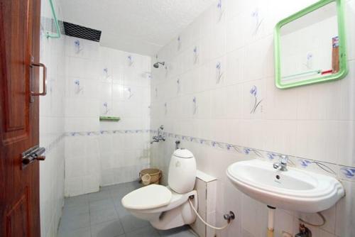 a white bathroom with a toilet and a sink at Bhanu Residency in Tirupati