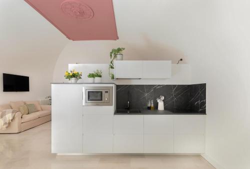 パレルモにあるPalazzo Ventimiglia Lodge & Suitesの白いキャビネットと電子レンジを備えたキッチン