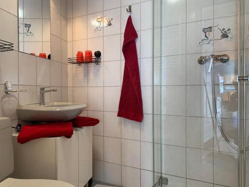 W łazience znajduje się umywalka, prysznic i czerwone ręczniki. w obiekcie Chasa Bazzi w mieście Scuol