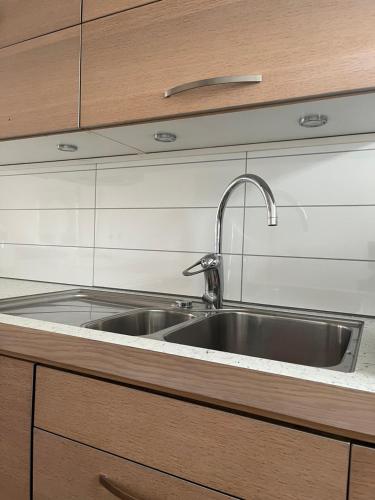 a kitchen with a stainless steel sink and wooden cabinets at Nära till allt in Falkenberg