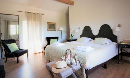 a bedroom with a large white bed and a chair at Domaine Le Bois Des Dames in Chantemerle-lès-Grignan