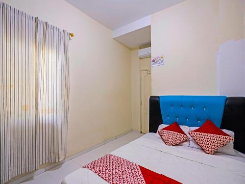 Un dormitorio con una cama con almohadas rojas. en OYO 92451 Hasan House Syariah 2, en Nagoya
