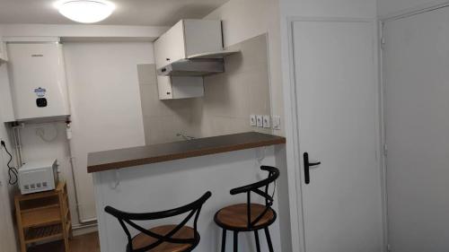 - une cuisine avec 2 chaises noires et un comptoir dans l'établissement Verdier Studio Lot 1, à Toulouse